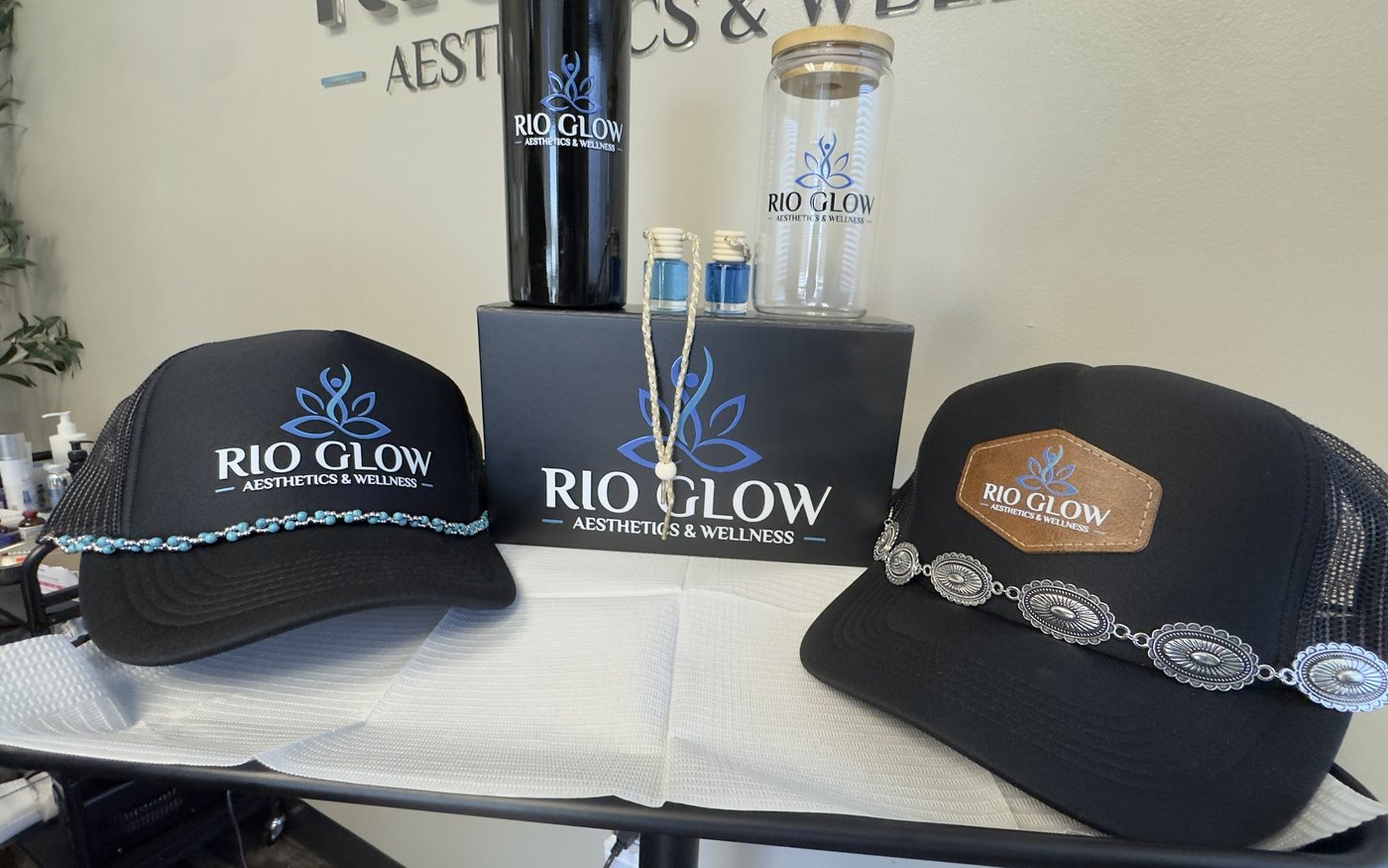 Two black trucker hats, one with a printed logo and a turquoise bead chain, one with a leather patch and a silver concho chain